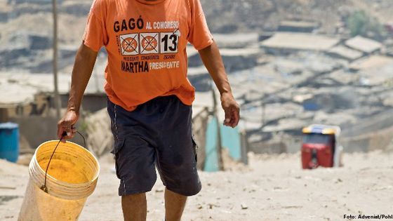 Mann mit einem Eimer auf den staubigen Straßen von Pamplona Alta, einem Armenviertel in Lima. Foto: Adveniat/Pohl.