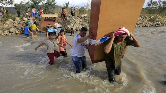 Abgeschobene Kolumbianer tragen ihr Hab und Gut durch den Grenzfluss Río Táchira auf die kolumbianische Seite hinüber. Foto: Reuters